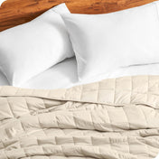 Close up of a weighted blanket on a bed next to pillows