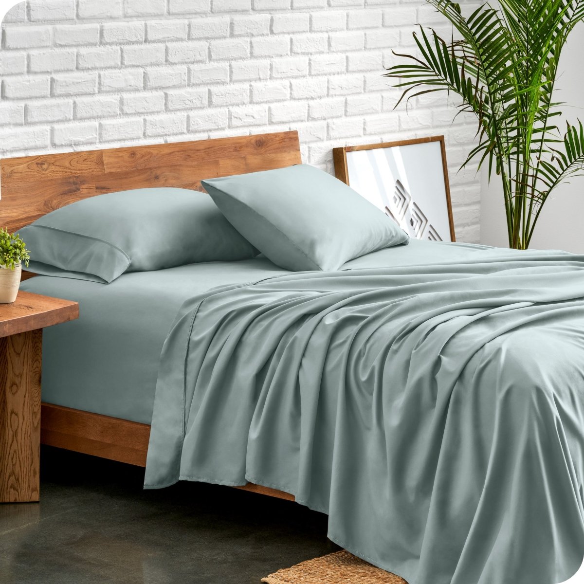 Bed with microfiber sheets against a white brick wall