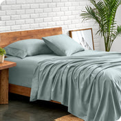Bed with microfiber sheets against a white brick wall