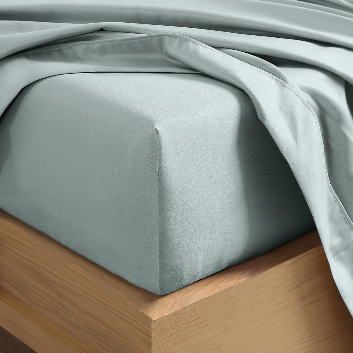 Close up of the corner of a mattress with a fitted sheet and flat sheet on it