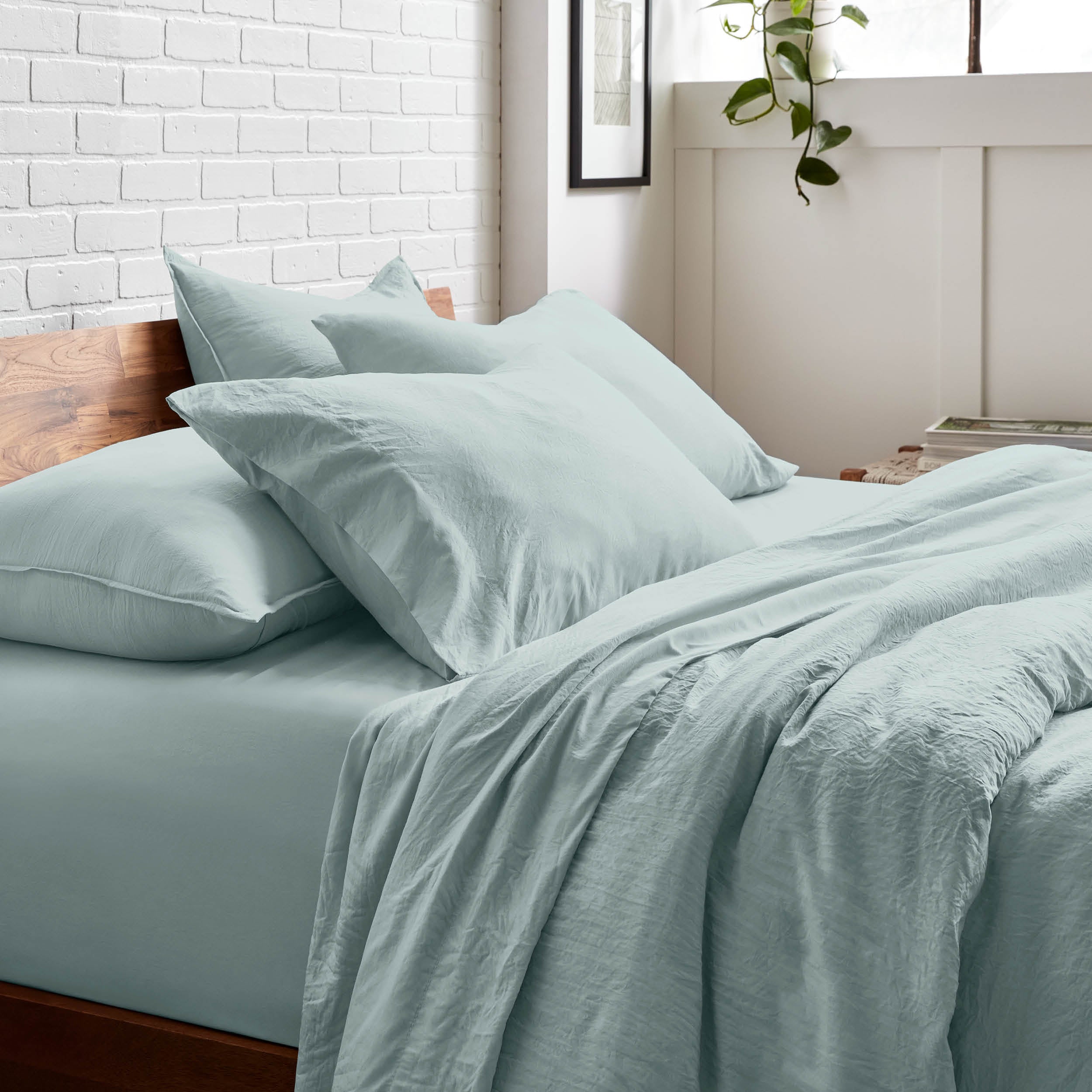 Bedding set on a bed with a white brick wall and window in the background