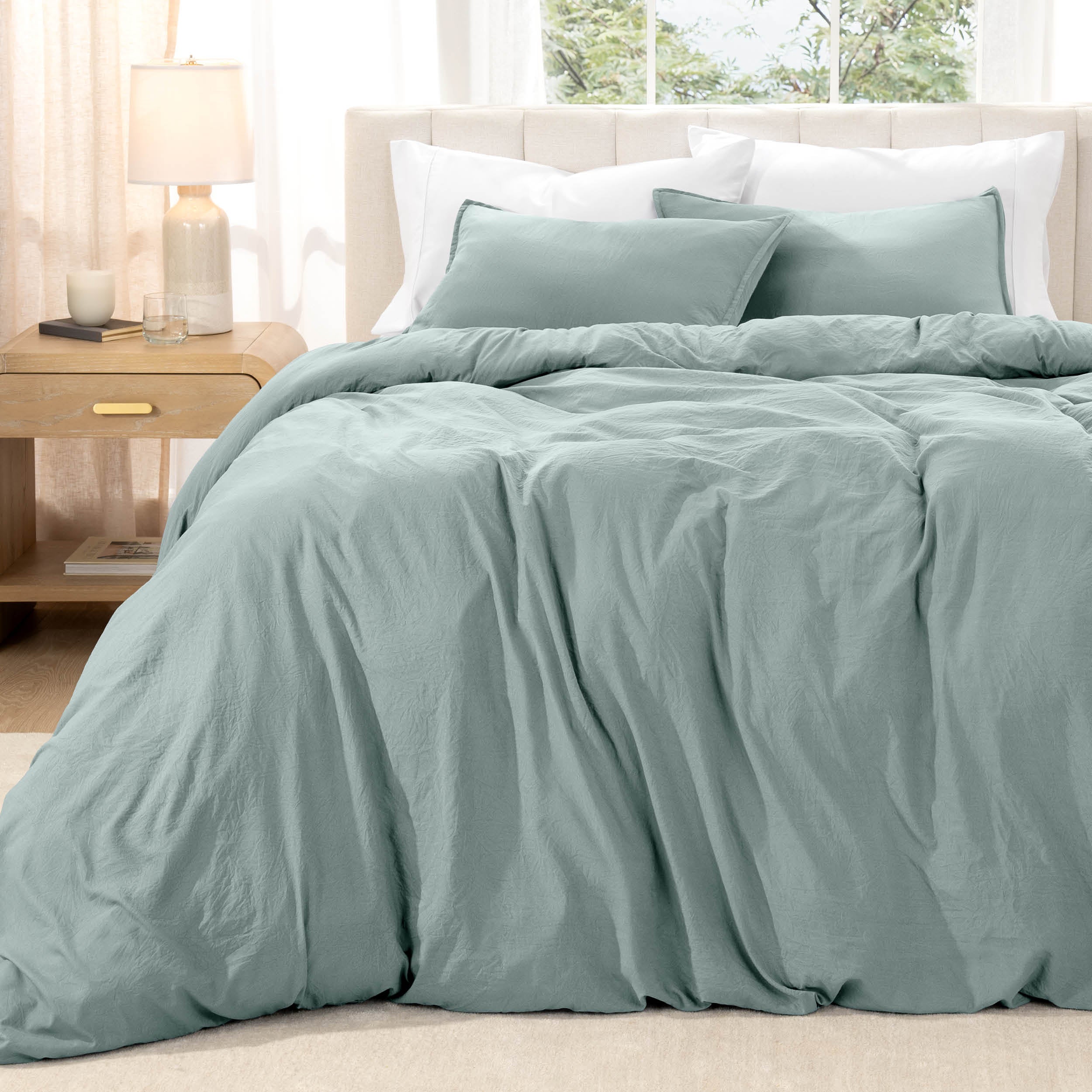 Bed with washed bedding and white pillows in a bright room