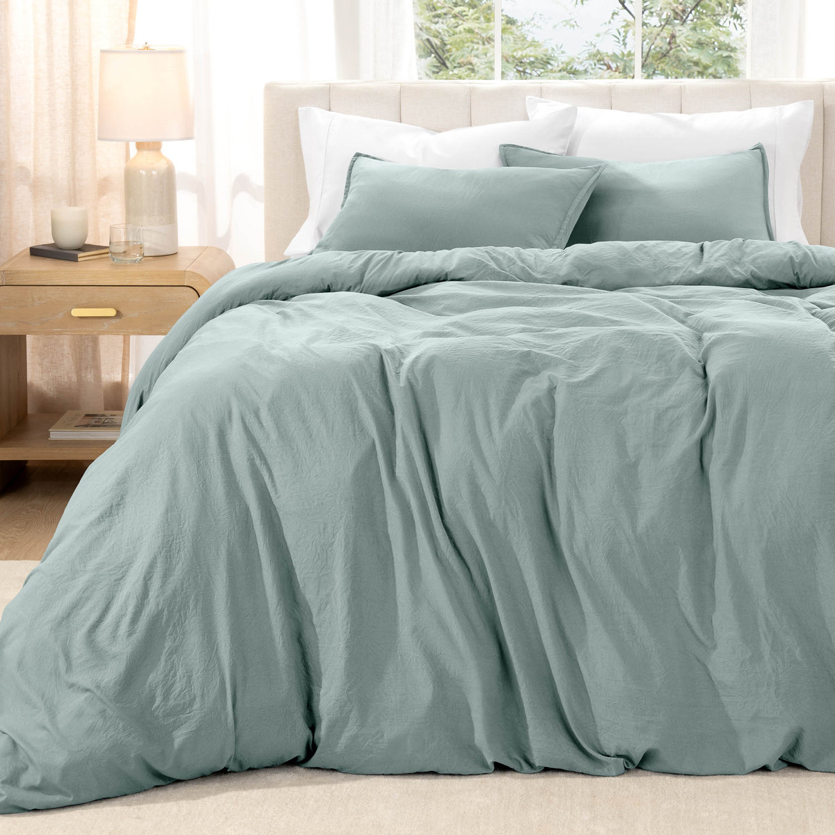 Bed with washed bedding and white pillows in a bright room