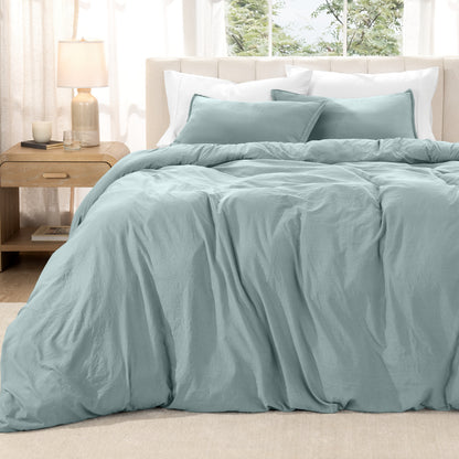 Washed duvet set on a bed in a bright bedroom with a lamp and window.