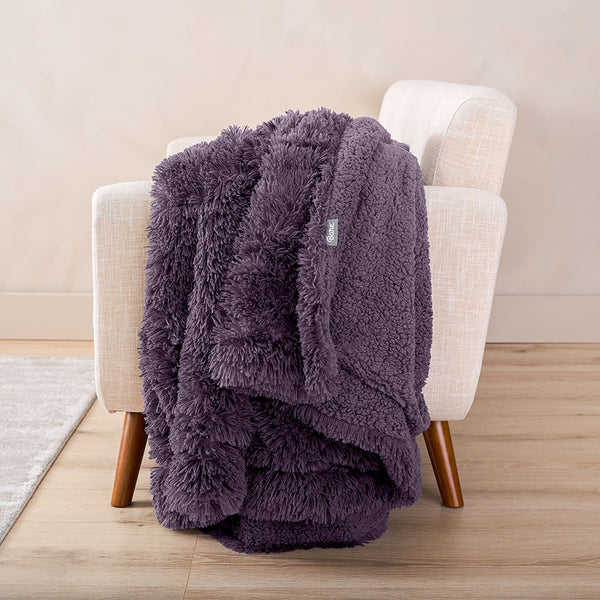 Eggplant Shaggy Faux Fur Blanket hung over a white armchair