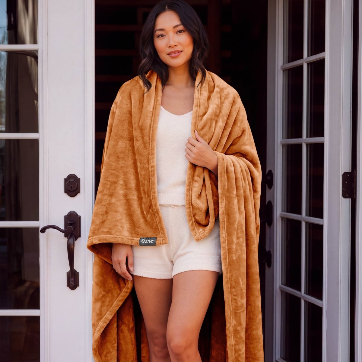 A woman standing with a microplush blanket wrapped around her