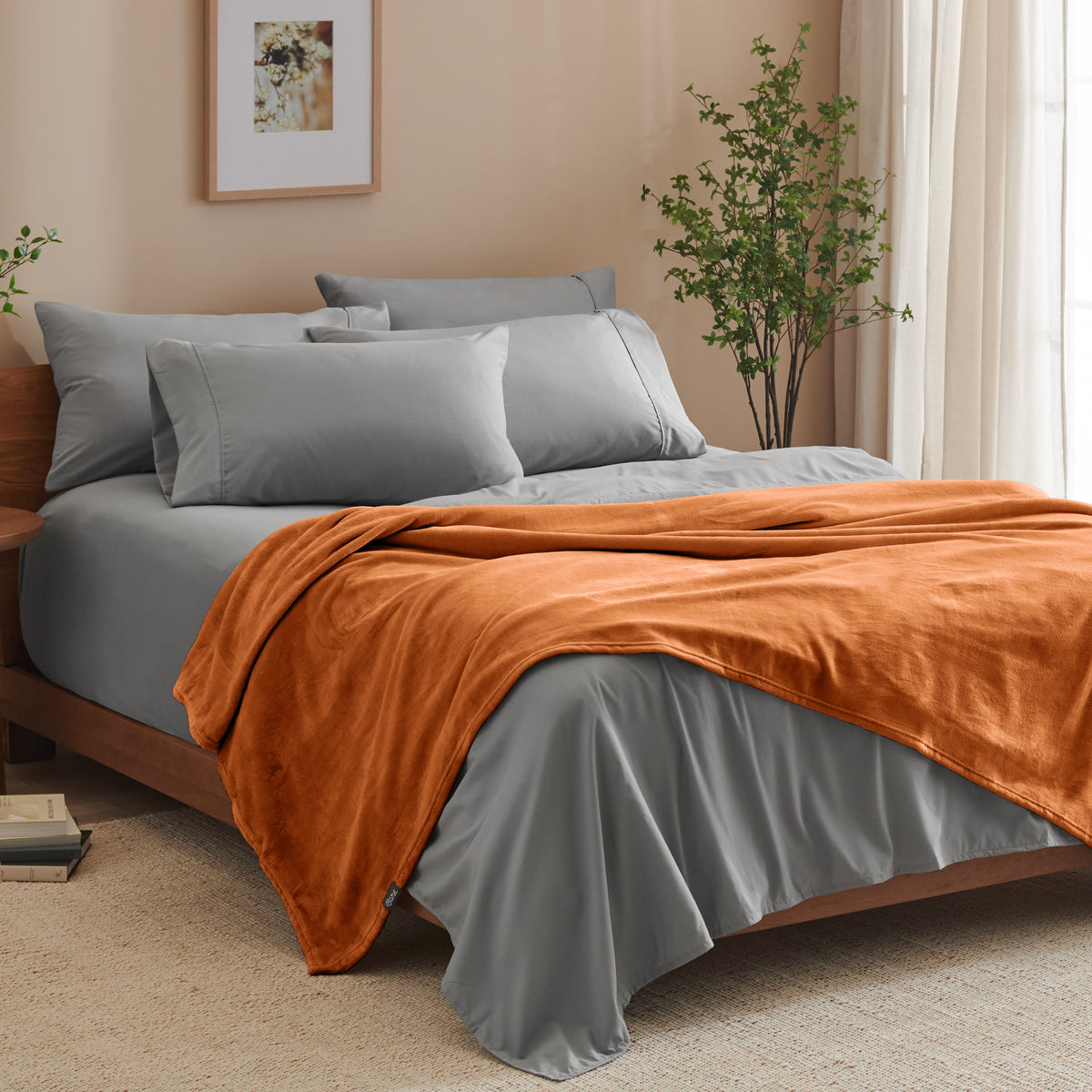 A bed made with grey sheets and a microplush blanket