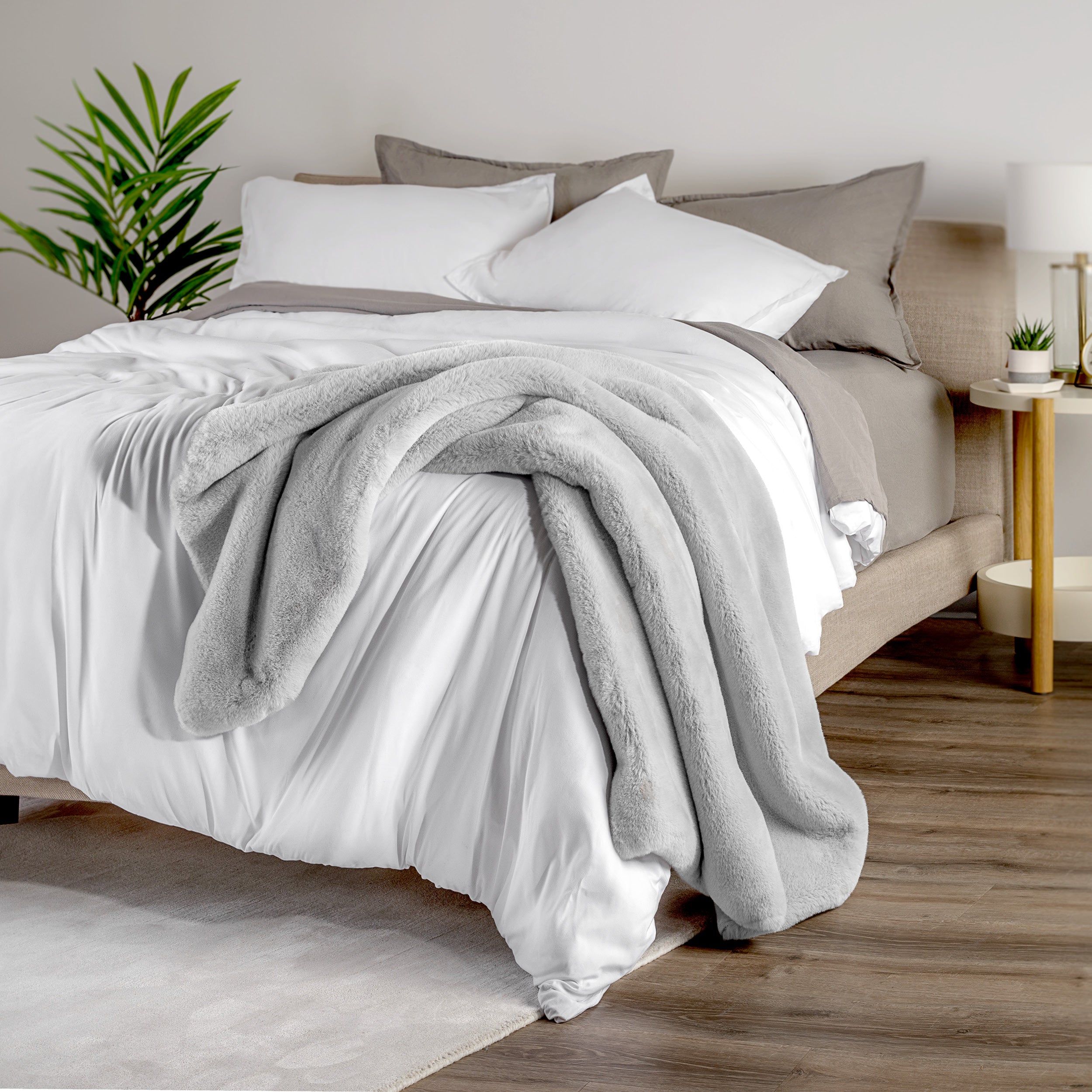 Blanket draped over a bed in a bedroom setting with a nightstand and lamp.