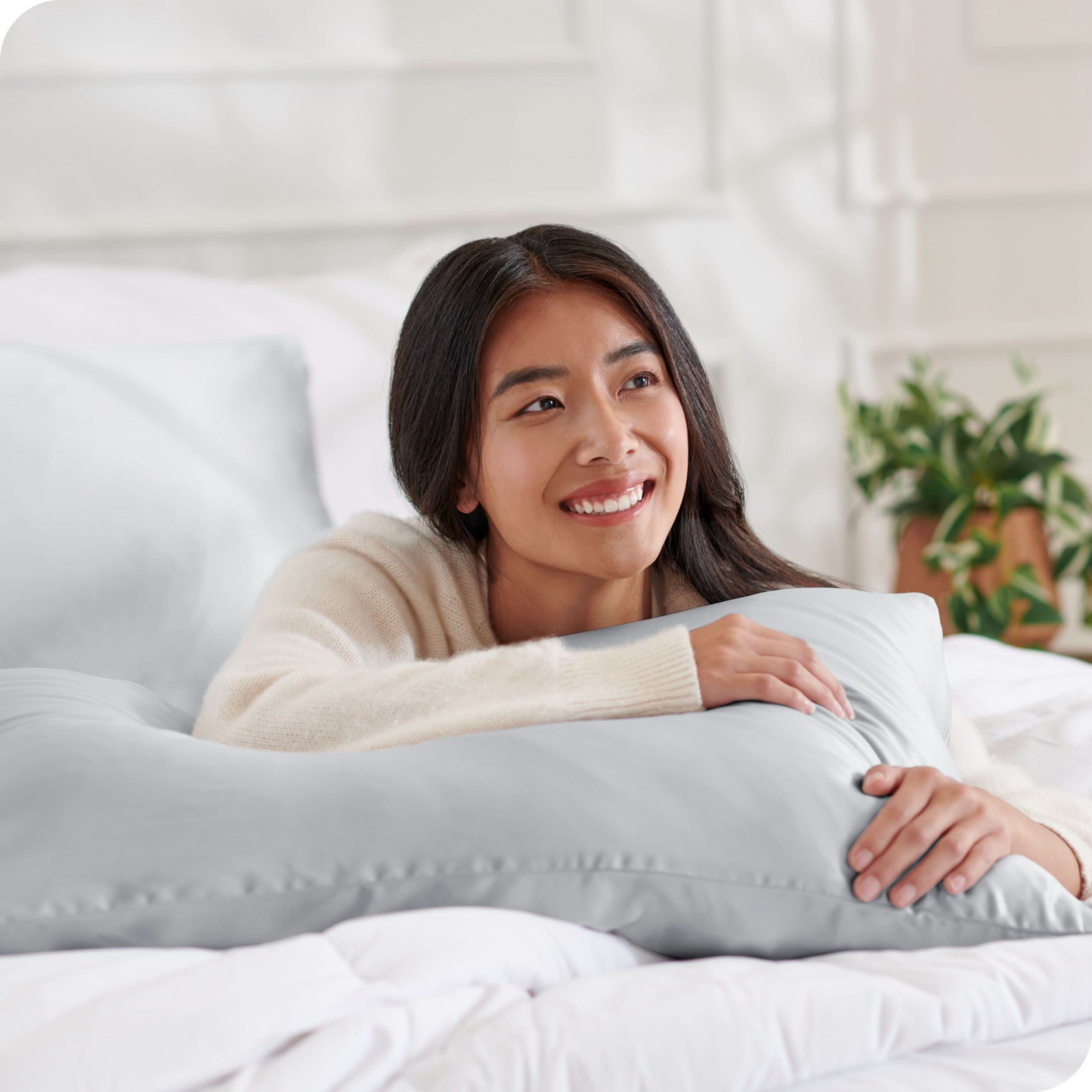 A woman on a bed with a silk pillowcase covered pillow