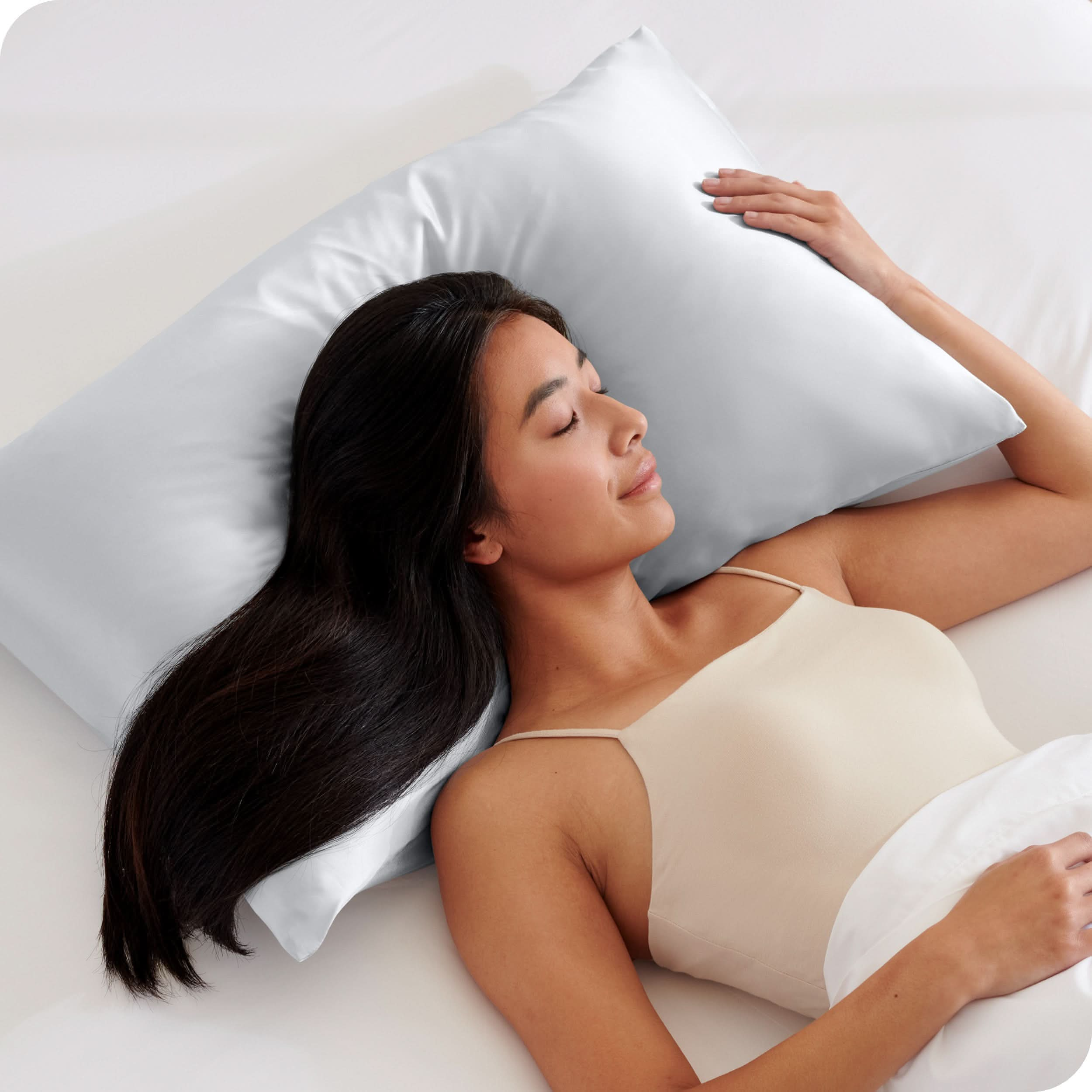 A woman is sleeping on a pillow with a satin pillowcase