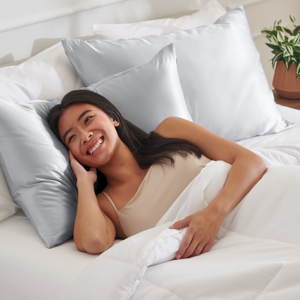 Woman lying on a bed with satin pillows and white bedding