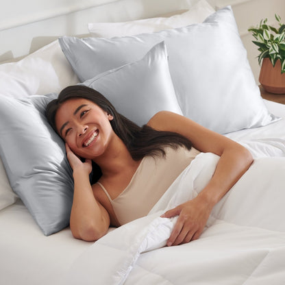 Woman lying on a bed with satin pillows and white bedding
