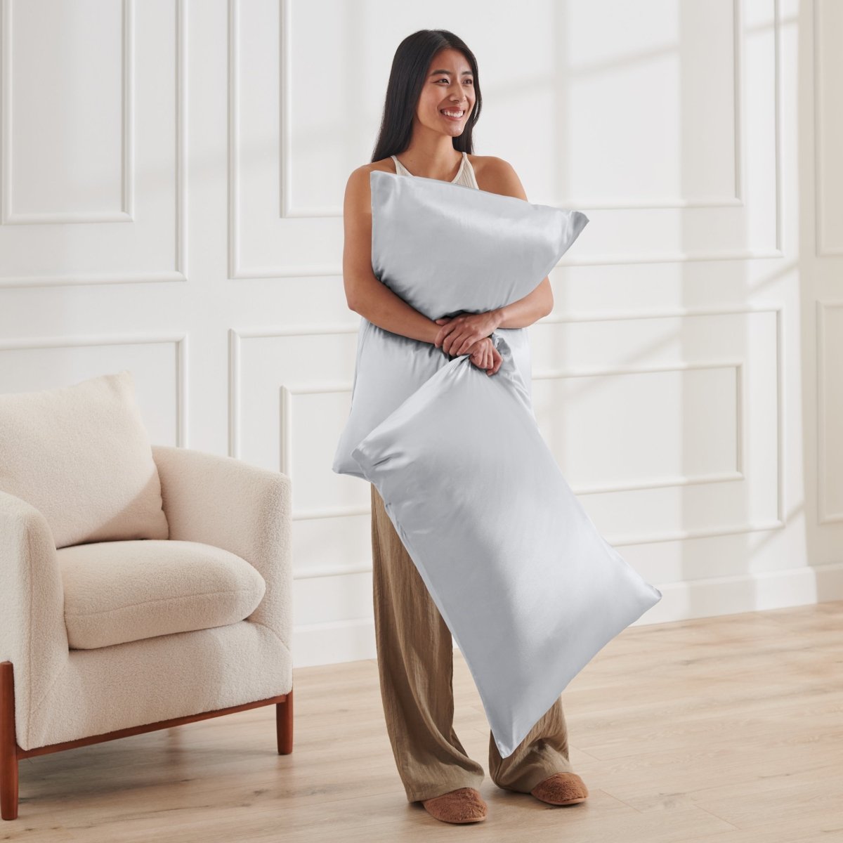 Woman holding 2 pillows with satin pillowcases on them