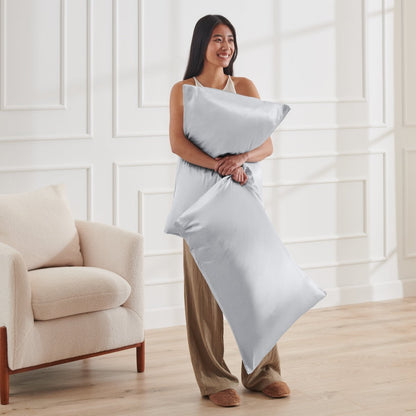 Woman holding 2 pillows with satin pillowcases on them