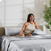 A woman is resting on a bed make with satin sheets