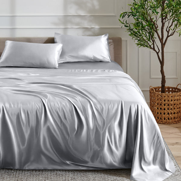 Satin sheet set on a bed with a plant and basket in the background