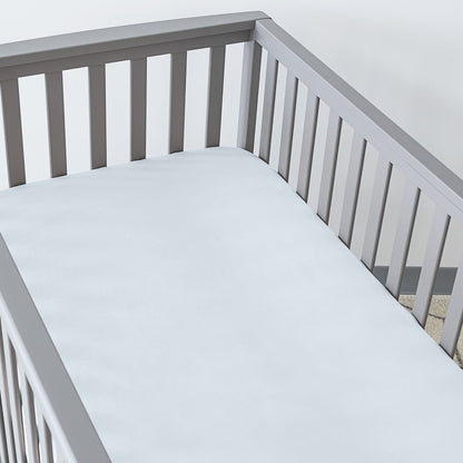 Gray crib with a fitted sheet on the mattress