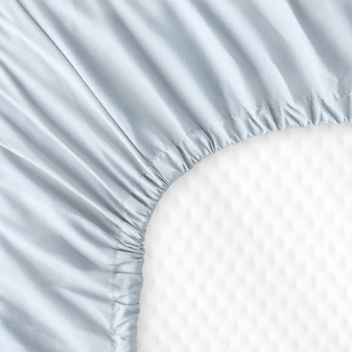 The back of a crib mattress with a fitted sheet on it
