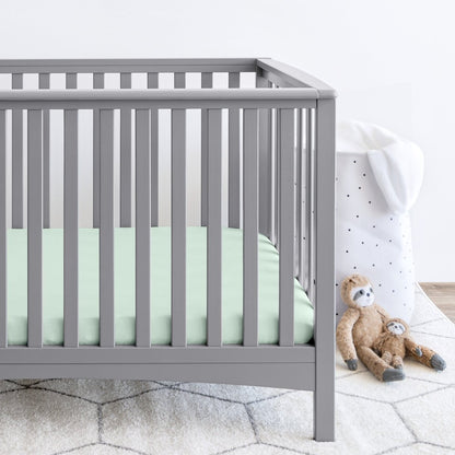Gray crib with stuffed animals on the floor next to it