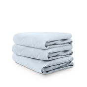 Stack of blue folded crib sheets on a white background