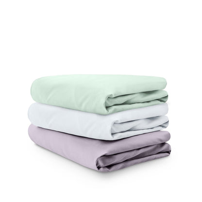 Stack of folded crib sheets on a white background