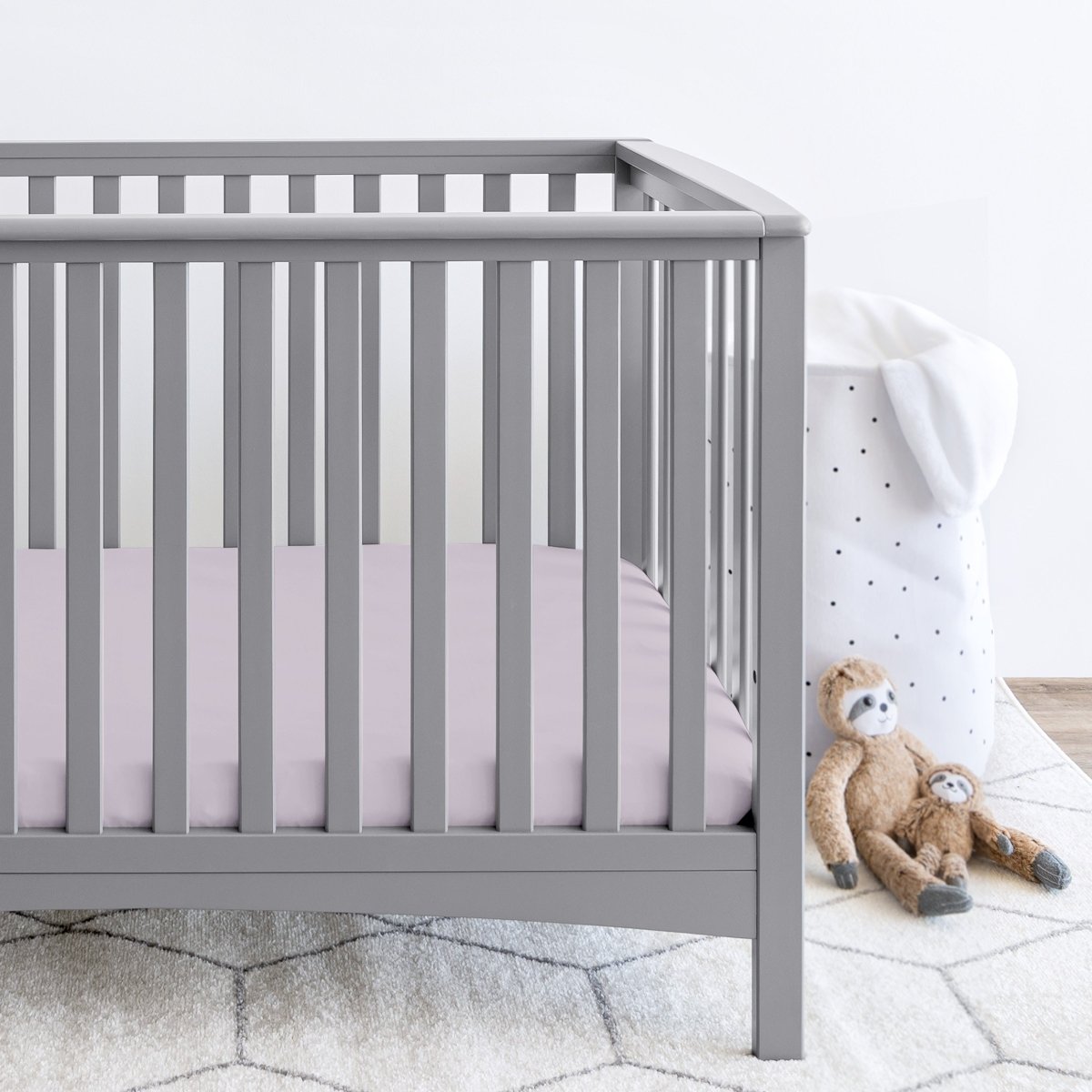 Gray crib with stuffed animals on the floor next to it