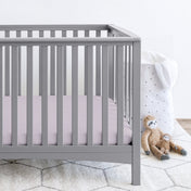 Gray crib with stuffed animals on the floor next to it