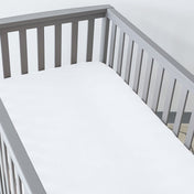 Gray crib with a fitted sheet on the mattress