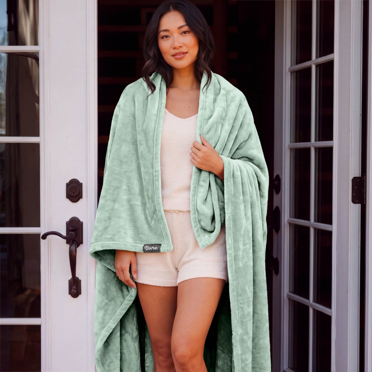A woman standing with a microplush blanket wrapped around her