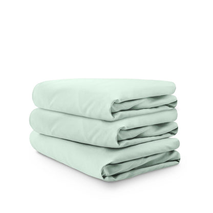 Stack of green folded crib sheets on a white background
