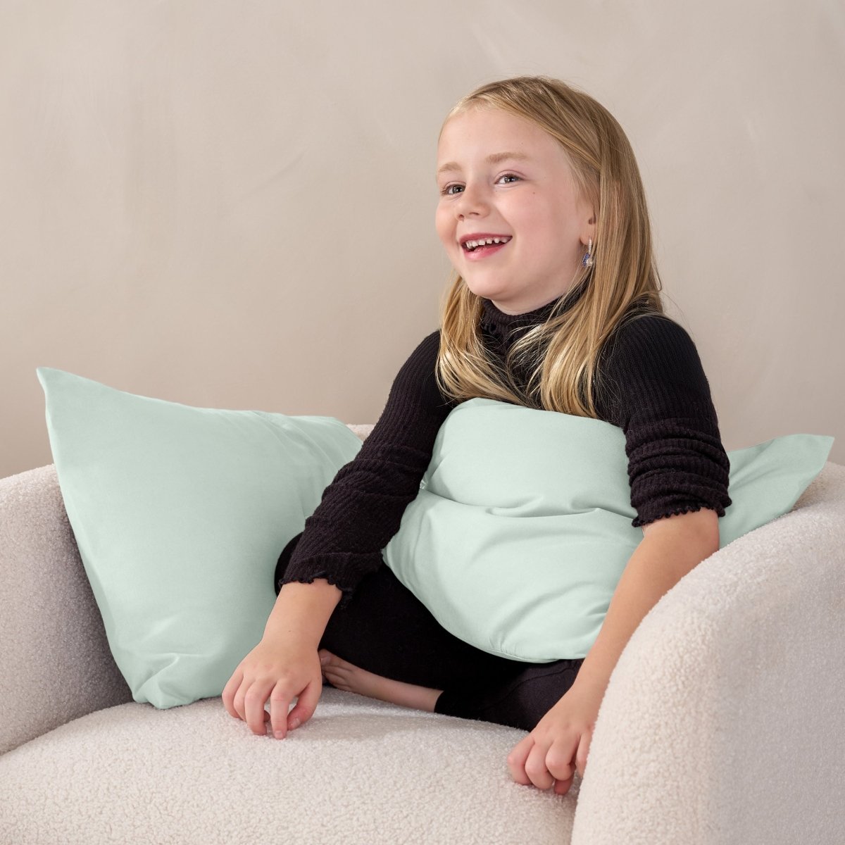 A child sitting while holding a microfiber pillowcase covered pillow