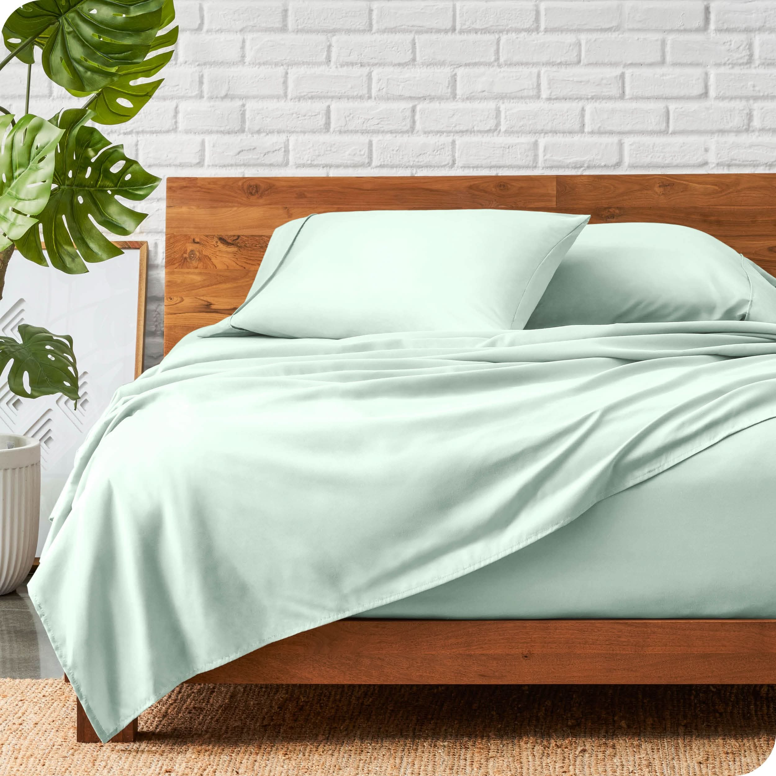 A wooden bed frame with a microfiber sheet set on the mattress.