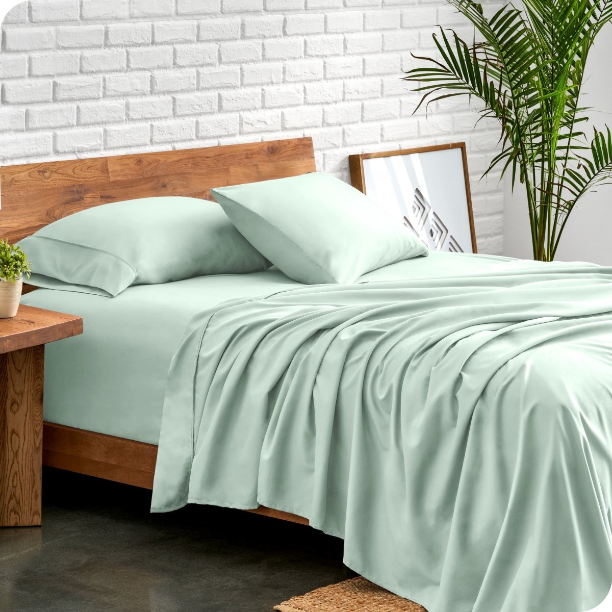 Bed with microfiber sheets against a white brick wall