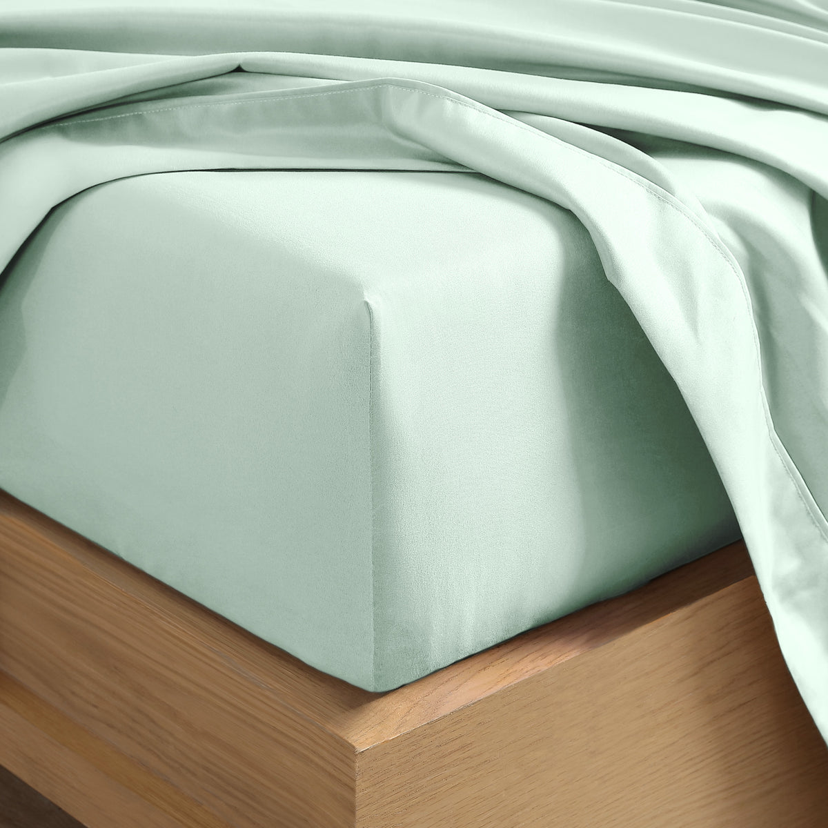 Close up of the corner of a mattress with a fitted sheet and flat sheet on it