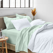 A side view of a bed made with microfiber sheets and a white duvet cover
