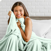 Woman sitting on a bed cuddling with a microplush blanket
