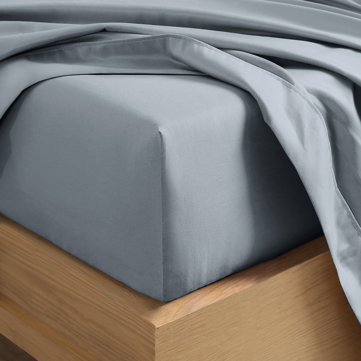Close up of the corner of a mattress with a fitted sheet and flat sheet on it