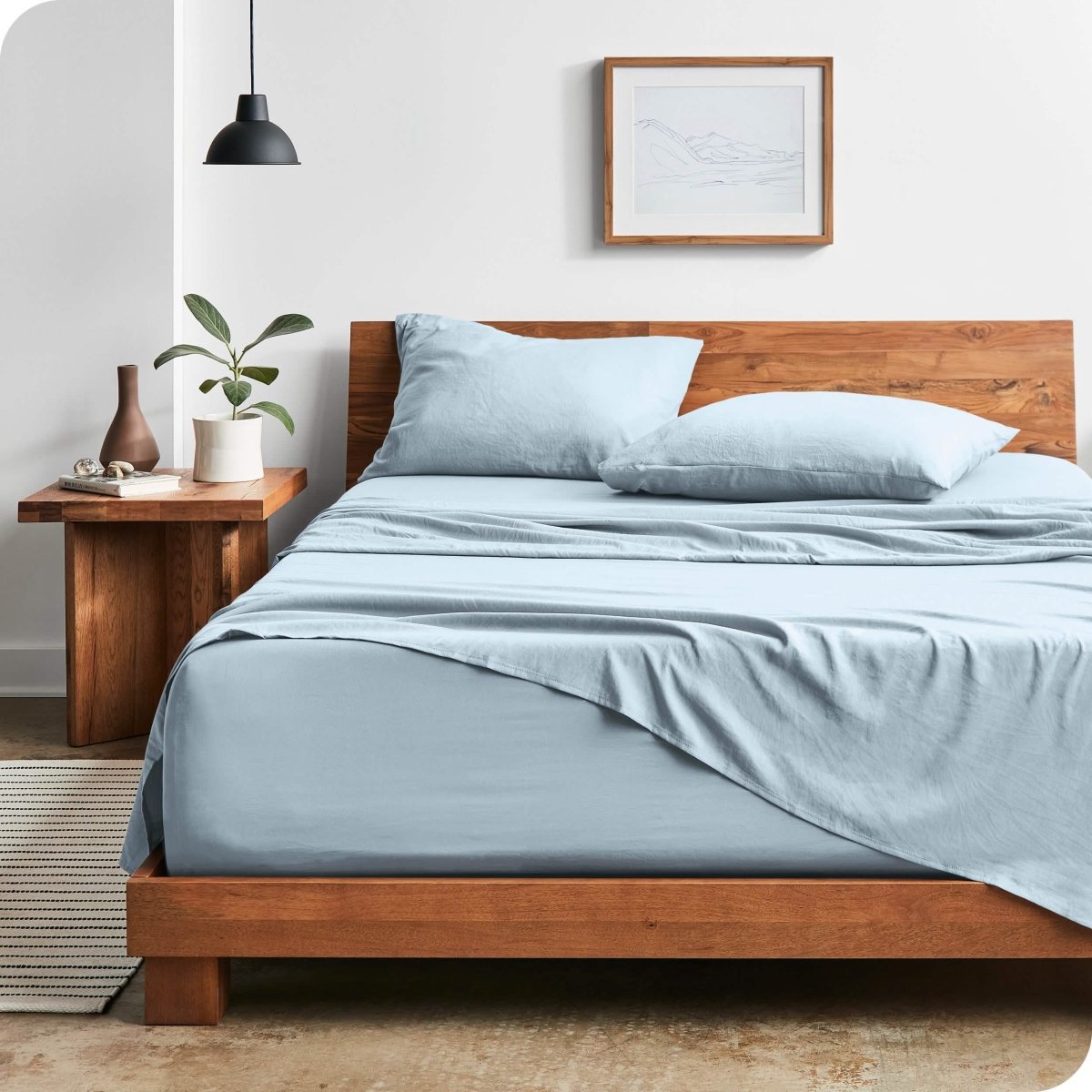 Modern bedroom with washed sheets draped over the end and the side of the bed