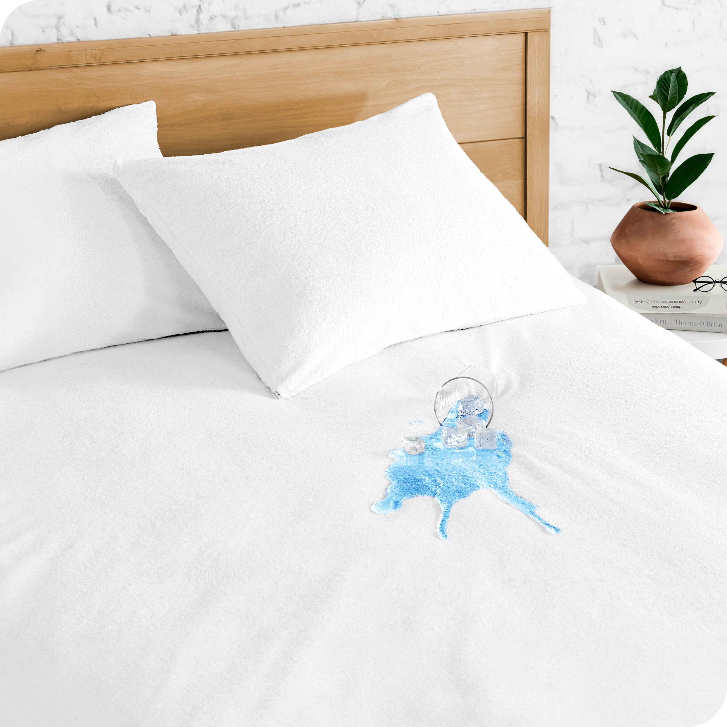 A glass of water spilled on a bed cover with a mattress protector