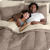 A couple is lying in bed with a comforter and sheets over them