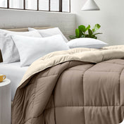 Close up of a comforter on a bed folded over itself. There are also 4 pillows on the bed.