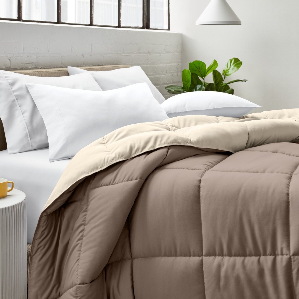 Bed with comforter and white pillows in a bright bedroom setting.