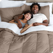 A couple is lying in bed with a comforter and sheets over them