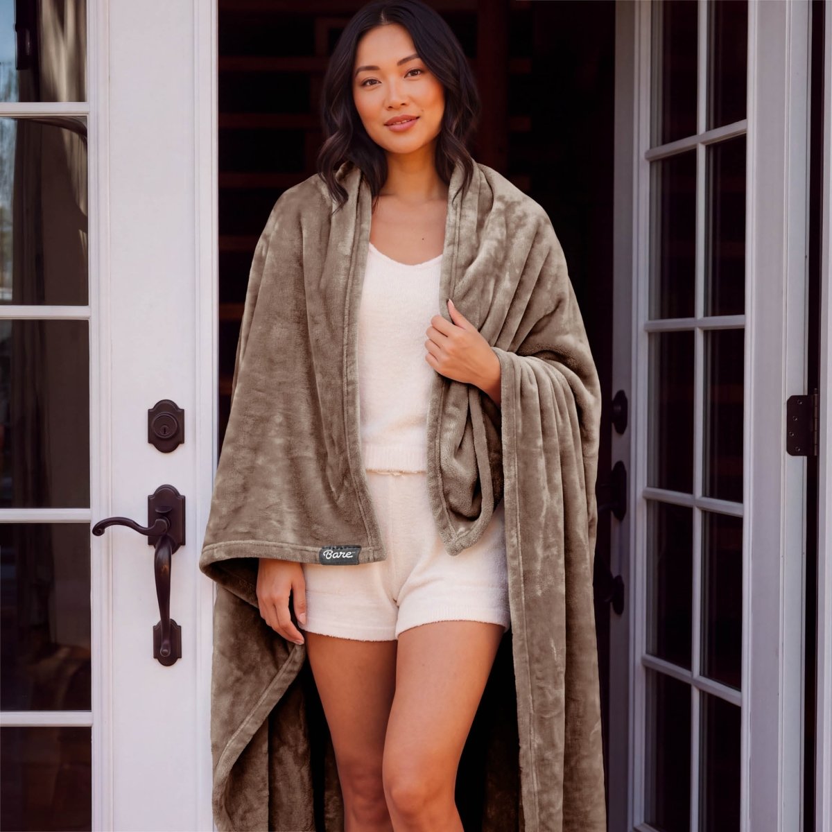 A woman standing with a microplush blanket wrapped around her