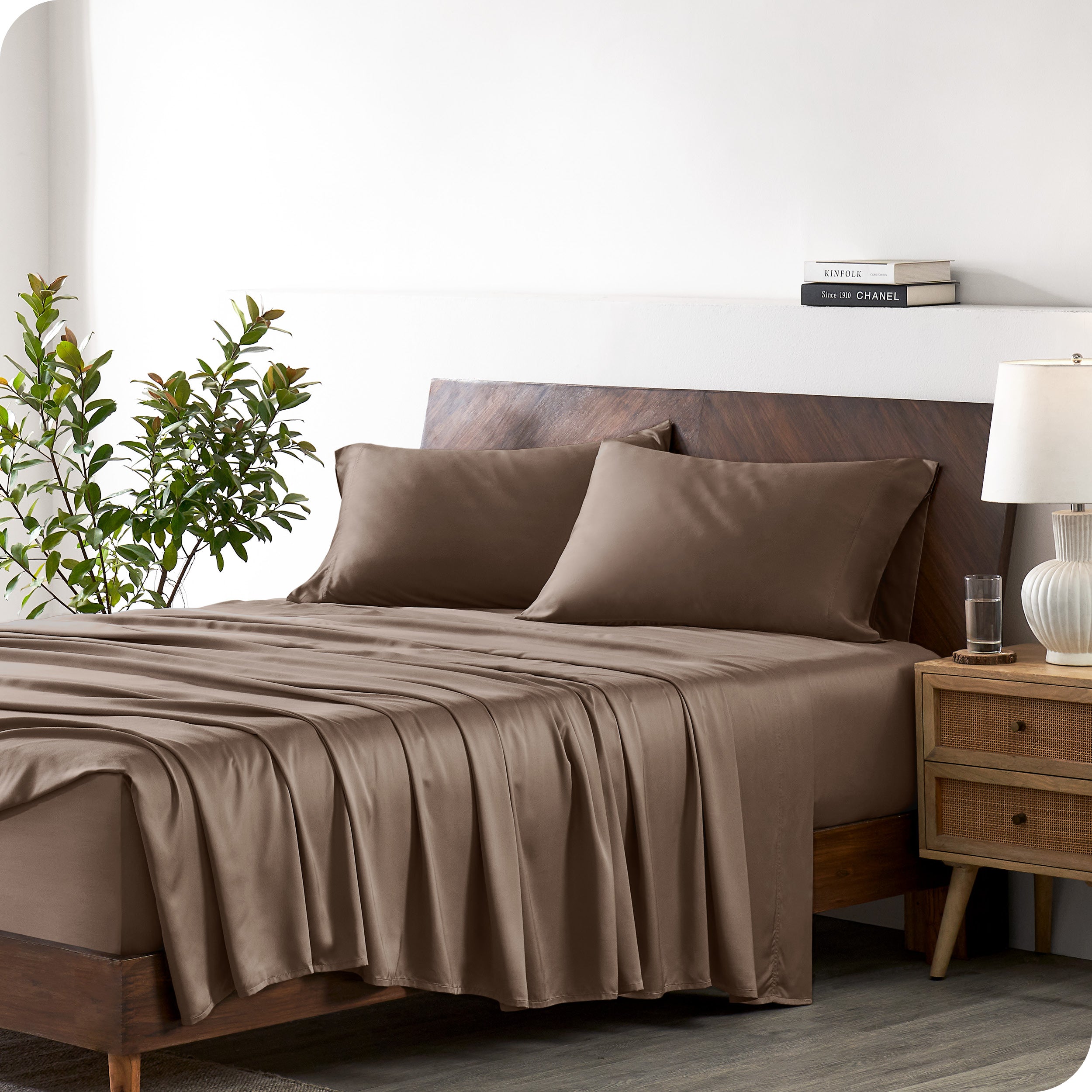 A bamboo sheet set draped over a bed with a wooden bed frame