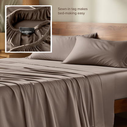 Bamboo sheets with a sewn-in tag on a wooden bed frame.