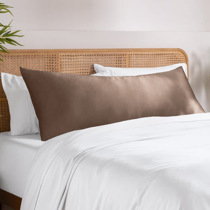 Body pillowcase on a pillow set on a bed with a wicker headboard and a plant in the corner.
