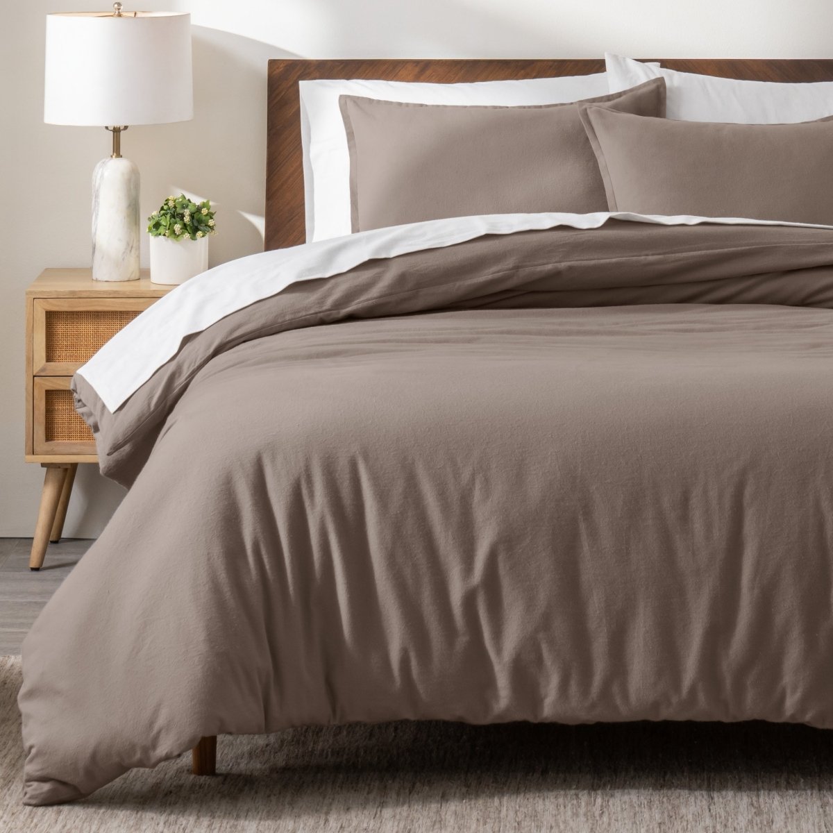 Flannel bedding set on a bed in a bedroom with a nightstand and lamp.