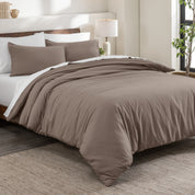 Flannel duvet cover set on a bed in a bedroom with a lamp and plant in the background.