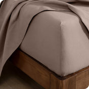 Corner of a bed with a flannel fitted sheet and top sheet on it